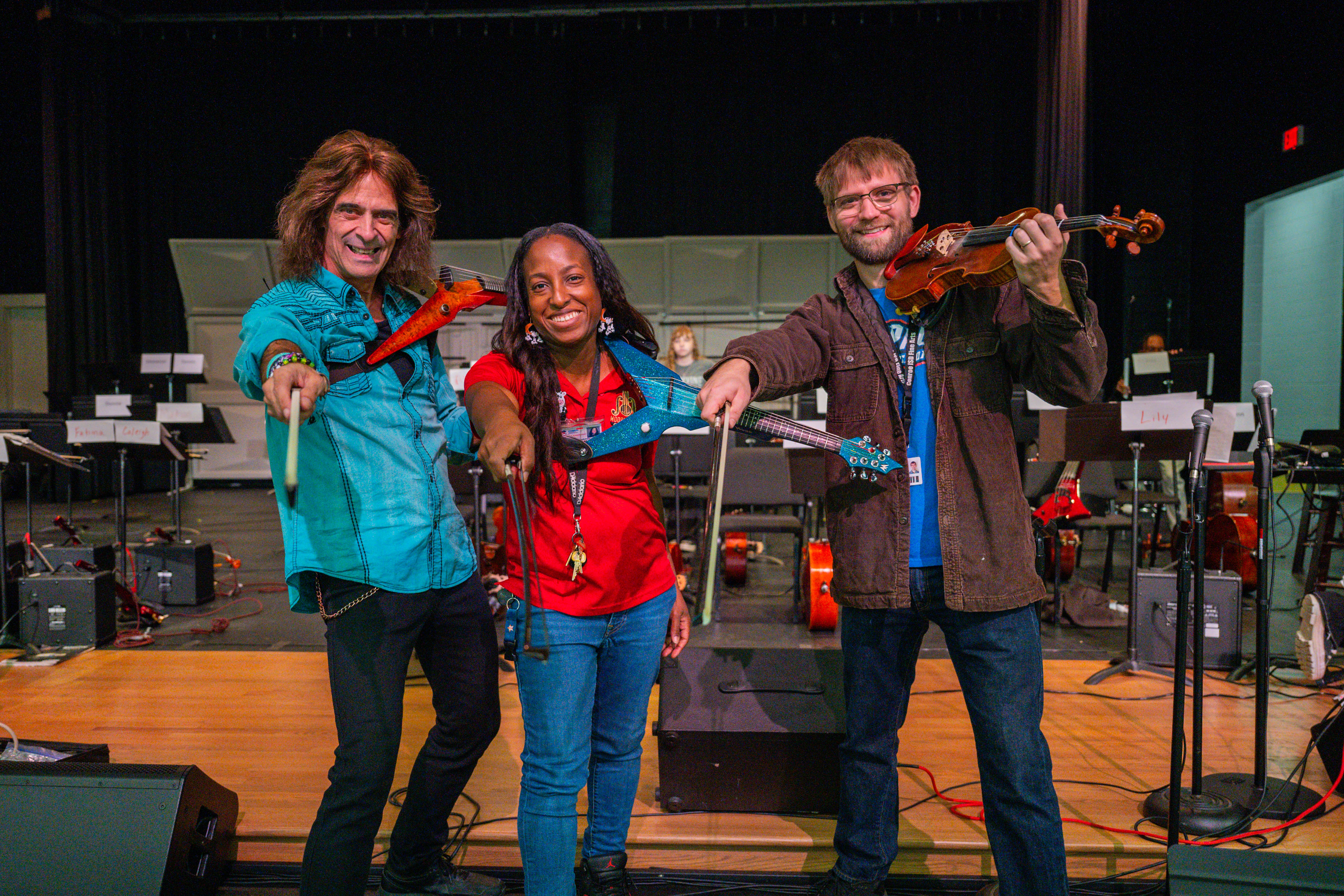 Educators holding up electric violins