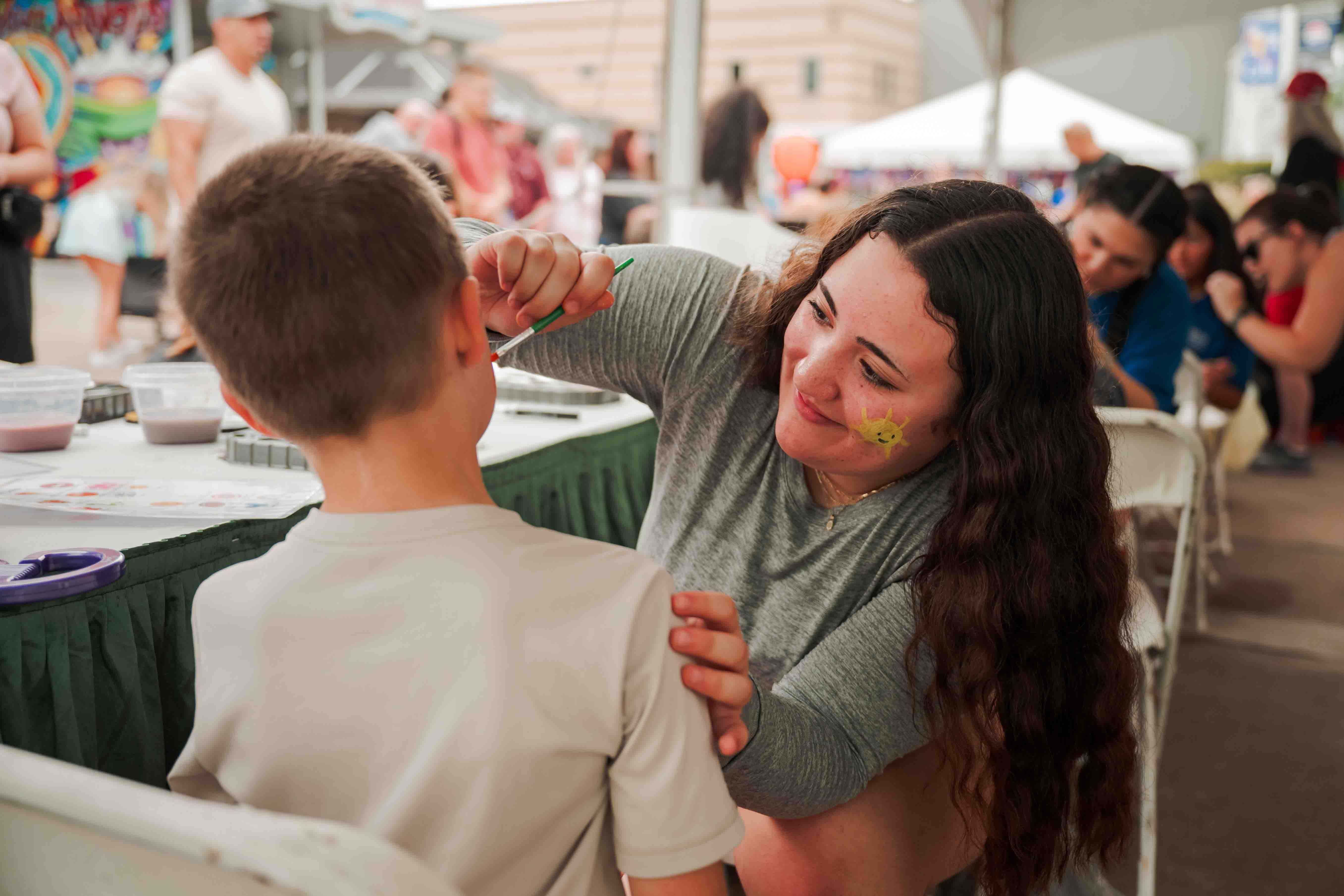 A volunteer helps children with a colorful festival game.