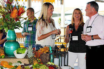 Two women and a man conversing with name tags and drinks