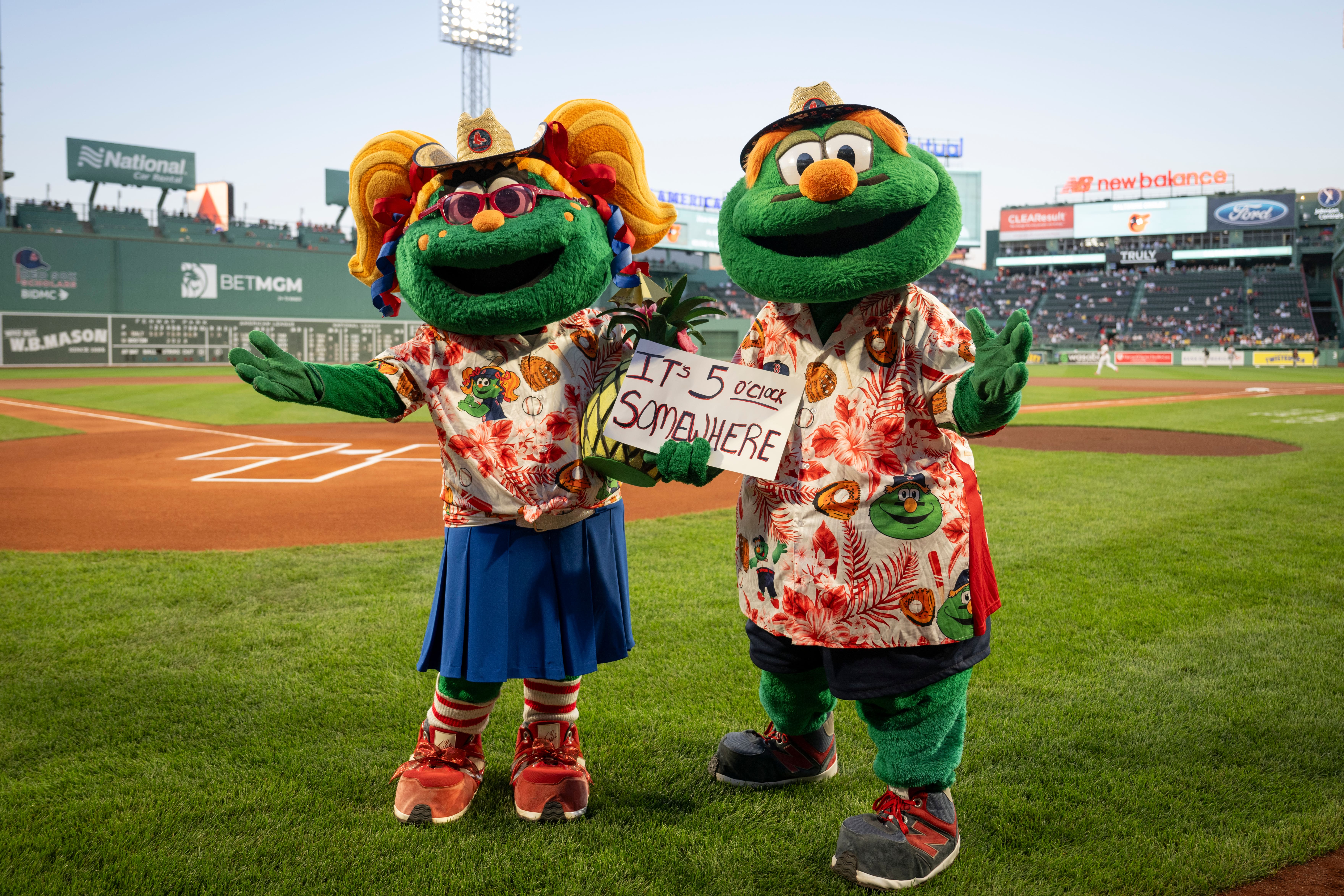 Boston Red Sox mascots Wally and Tessie posing in tropical outfits on the field at Fenway Park