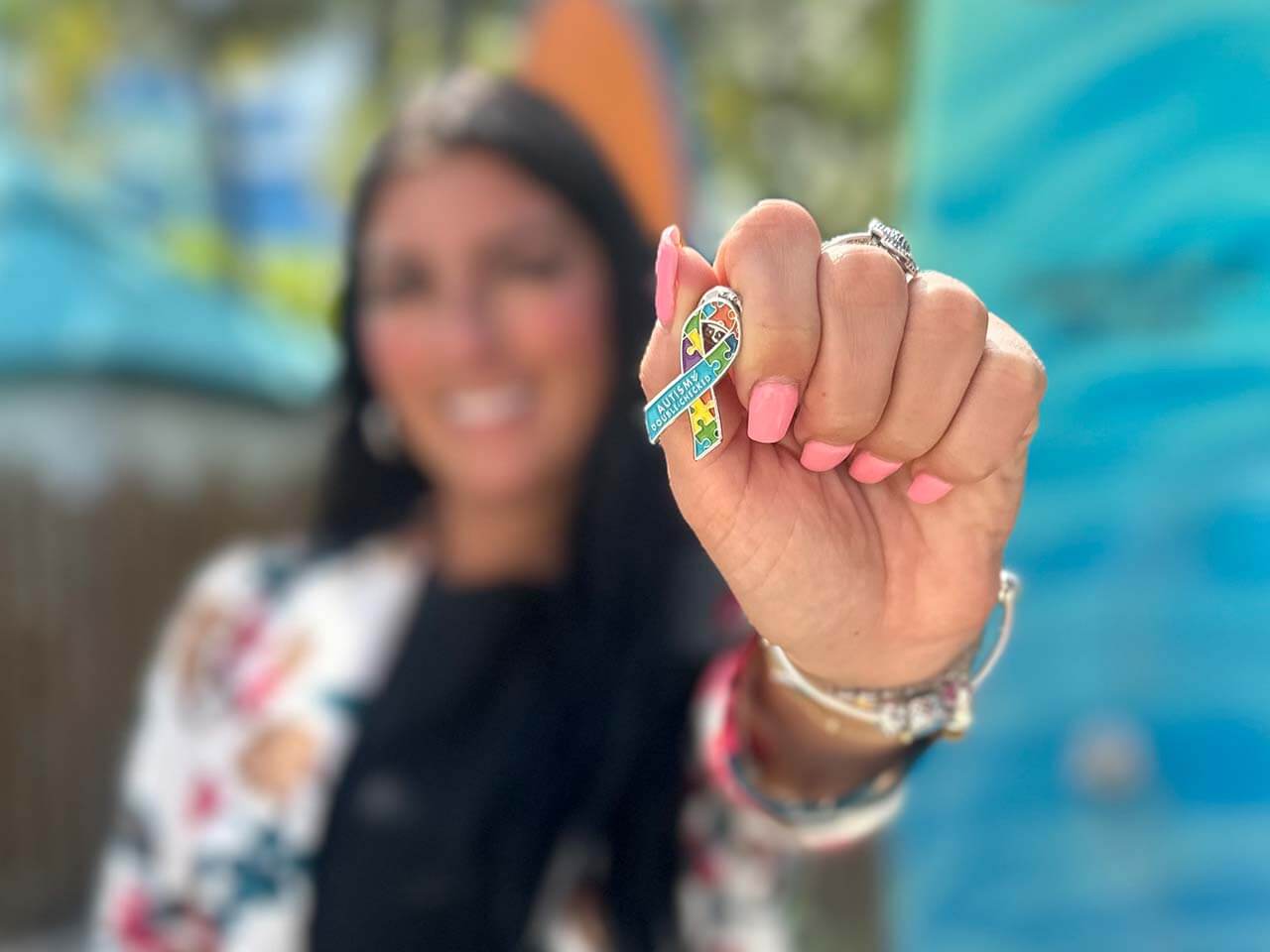 woman holding Autism pin up to the camera