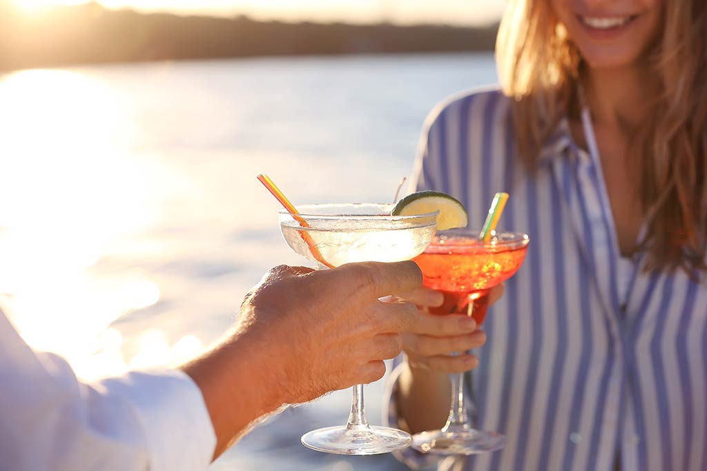 Two people holding glasses with cocktails